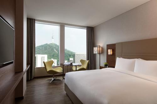 ソウルにあるコートヤード バイ マリオット ソウル 南大門のベッド、デスク、椅子が備わるホテルルームです。