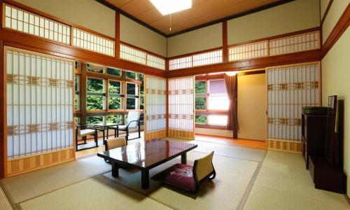 a room with a table and chairs and windows at Fujisan Ryokan in Hanamaki