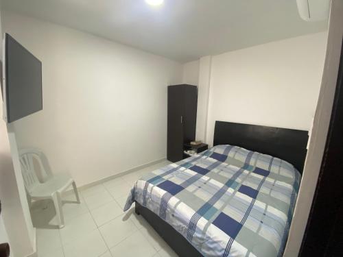 a bedroom with a bed and a chair in it at Cómodo apto 203 muy cerca a CENTRO COMERCIAL UNICENTRO CUCUTA in Cúcuta