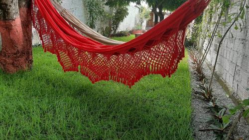 a red hammock hanging from a tree in a yard at Vila dos Bangalôs in Barreirinhas