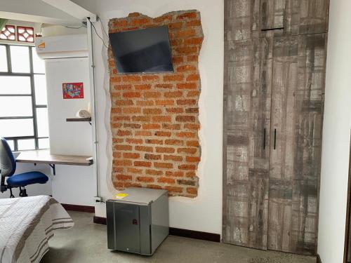 a room with a brick wall and a television on a wall at La Curva Apartamentos in Cali