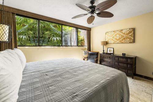 Schlafzimmer mit einem Bett, einem Deckenventilator und einem Schreibtisch in der Unterkunft Kona Makai 2103 in Kailua-Kona