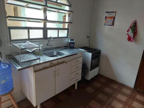 a small kitchen with a sink and a stove at Casa Guarujá c/ piscina grande in Guarujá