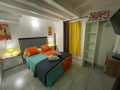 sypialnia z łóżkiem z pomarańczowymi poduszkami w obiekcie Kaza Mango w mieście Sainte-Luce