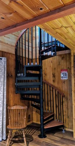 a spiral staircase in a cabin with a chair at Cabin #4 in Strawberry