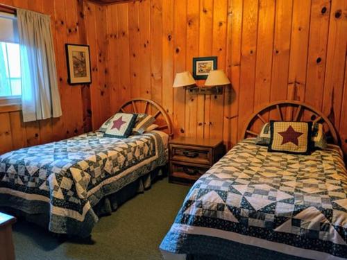 a bedroom with two beds and wooden walls at Cabin #5 in Strawberry