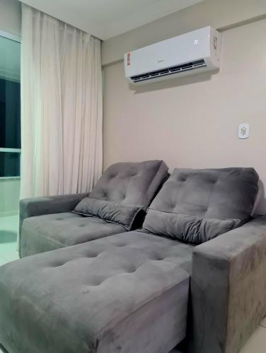 a living room with a couch and a air conditioner at APARTAMENTO À BEIRA MAR - PÉ NA AREIA - Ilhéus in Ilhéus