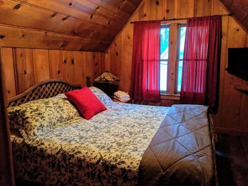 a bedroom with a bed with a red pillow on it at Cabin #7 in Strawberry