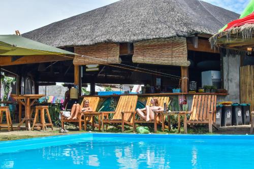 a resort with a pool and chairs and a thatch roof at Mad Monkey Hostel Siargao in General Luna