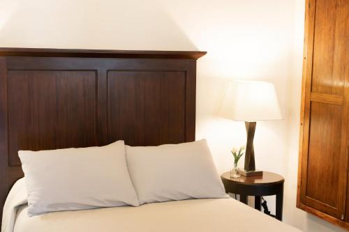 a bedroom with a bed with a wooden headboard and a lamp at La Casa Veintidós in Guanajuato