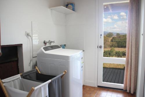 a laundry room with a washing machine and a window at Yackandandah farm homestead in Yackandandah