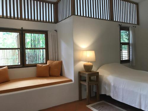 a bedroom with a bed and two windows and a lamp at resort hoshihana in Chiang Mai