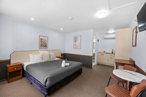 - une chambre avec un lit, une table et des chaises dans l'établissement Bent Street Motor Inn, à Grafton