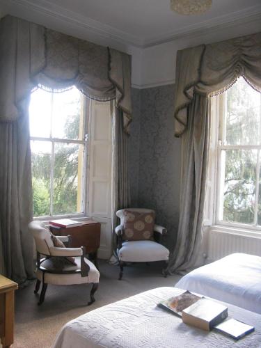 a bedroom with two beds and a desk and two windows at Flemings Country House in Cork