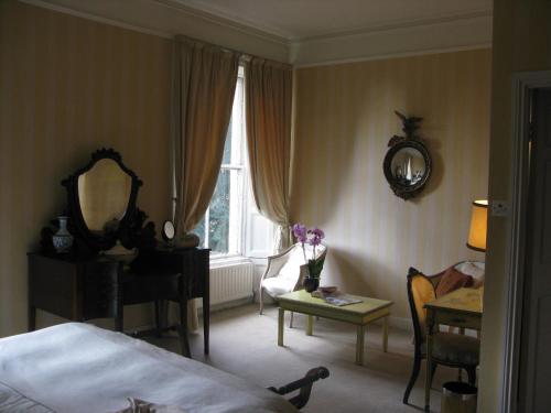 a bedroom with a bed and a table and a mirror at Flemings Country House in Cork