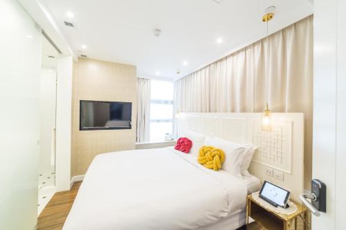 a white bedroom with a large white bed and a tv at Tung Nam Lou Art Hotel in Hong Kong