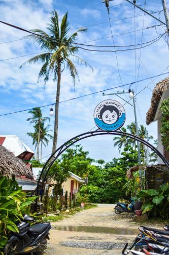 an archway with a sign over a street with motorcycles at Mad Monkey Hostel Siargao in General Luna