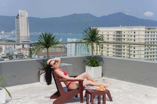a woman sitting in a chair on a roof at Hotel Soco in Da Nang