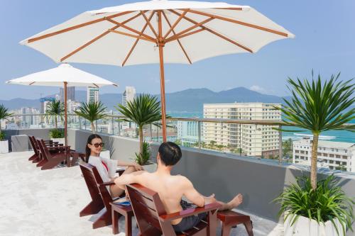 two people sitting on a balcony with an umbrella at Hotel Soco in Da Nang