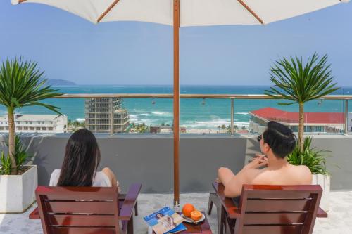 two women sitting in chairs looking out at the ocean at Hotel Soco in Da Nang
