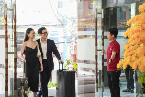 a man and woman with a suitcase in front of a building at Hotel Soco in Da Nang