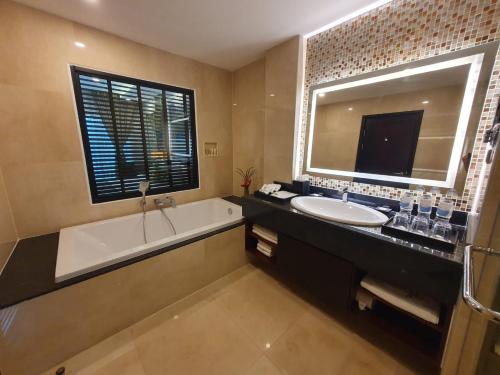 y baño con bañera, lavabo y espejo. en Tmark Resort Vangvieng en Vang Vieng