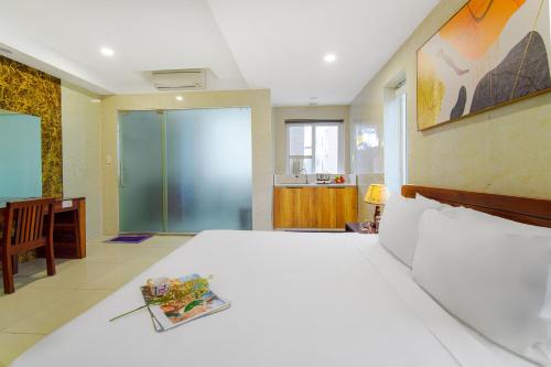 a bedroom with a large white bed and a kitchen at Hotel Soco in Da Nang