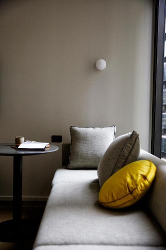 a couch with a yellow pillow next to a table at A by Adina Sydney in Sydney