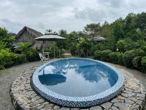 a swimming pool with a chair and an umbrella at VulunVili Homestay in Tây Ninh