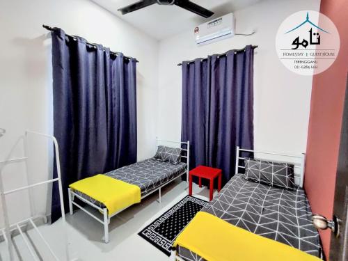 2 camas en una habitación con cortinas moradas en Tamu Homestay Terengganu en Kuala Terengganu