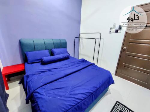 a bed with blue sheets and a red chair in a room at Tamu Homestay Terengganu in Kuala Terengganu