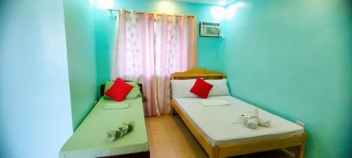 2 Betten in einem Zimmer mit roten und blauen Wänden in der Unterkunft RNA Guesthouse in Moalboal