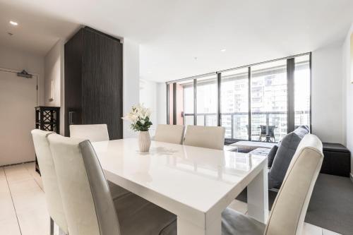 a white dining room with a white table and chairs at ◈Melbourne CBD 2Br 2Bth Apt Indoor Pool & balcony◈ in Melbourne
