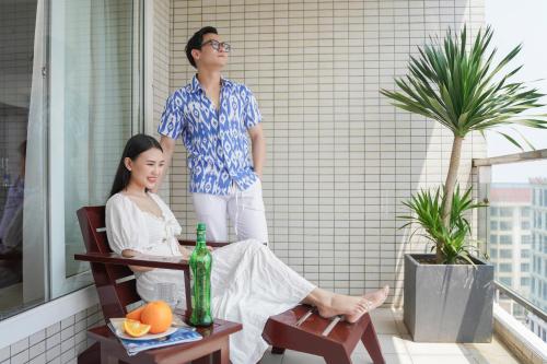 a man standing next to a woman sitting in a chair at Hotel Soco in Da Nang