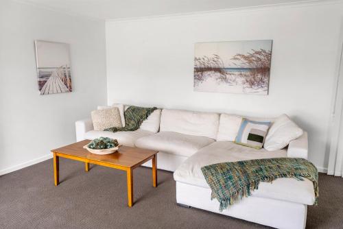 a living room with a white couch and a table at Surfs Up! Oceanfront Home Sleeps 6 steps from the sand in Emerald Beach