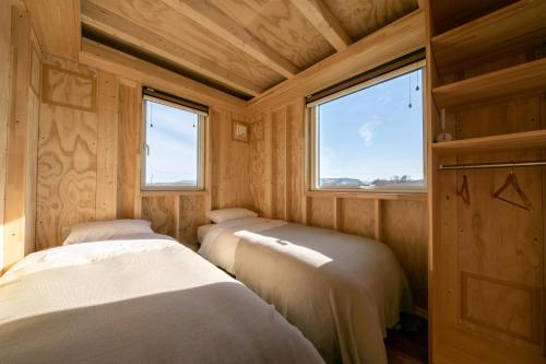 Okhotsk Ocean Villa AL MARE mombetsu في مونبيتسو: غرفة بثلاث اسرة في غرفة صغيرة