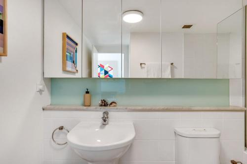 a white bathroom with a sink and a mirror at Sunchaser at Iluka Resort Apartments in Palm Beach