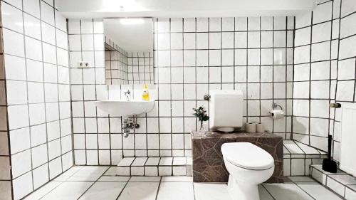 a white tiled bathroom with a toilet and a sink at Work & Stay Apartments in Rheine in Rheine