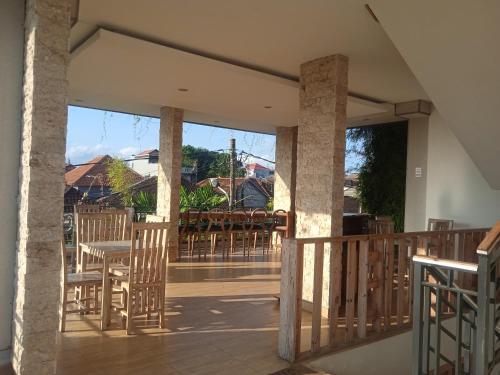 een veranda met stoelen en tafels op een terras bij MURAI Guesthouse Bali in Denpasar