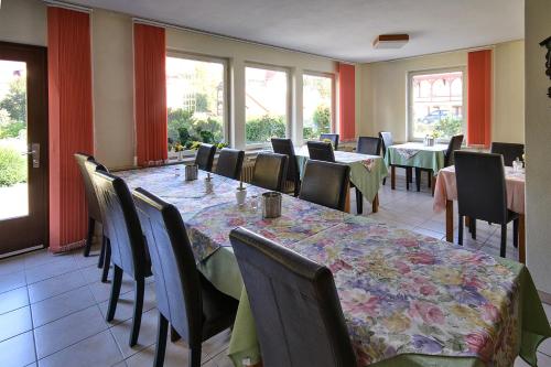 ein Esszimmer mit Tischen, Stühlen und Fenstern in der Unterkunft Haus Erika in Bad Sooden-Allendorf