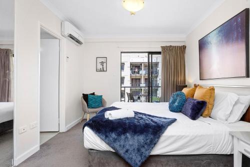 a bedroom with a large white bed with blue pillows at 309 Secret City Sanctuary Prkingpoolview in Perth