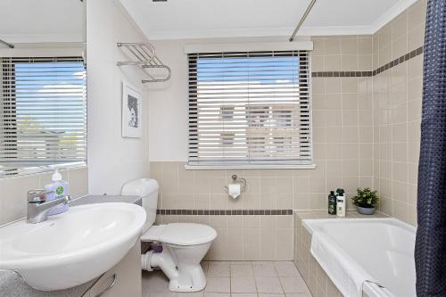 a bathroom with a sink and a toilet and a tub at 309 Secret City Sanctuary Prkingpoolview in Perth