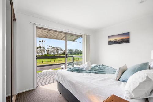 a bedroom with a bed and a large window at Surfs Up! Oceanfront Home Sleeps 6 steps from the sand in Emerald Beach