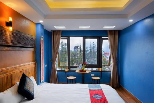Un dormitorio azul con una cama y una mesa con sillas. en Le Petit Gecko Hotel en Sa Pa