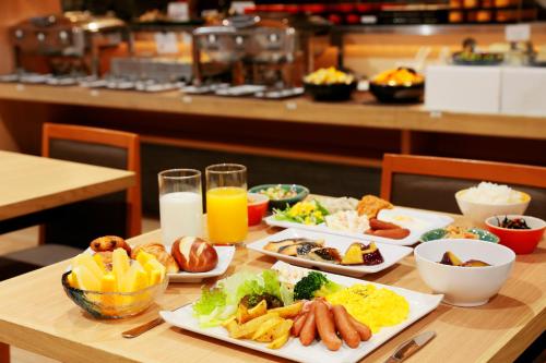 a table with plates of food and glasses of orange juice at Sotetsu Fresa Inn Tokyo Kinshicho in Tokyo