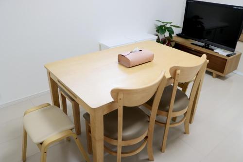 SAPPHIRE -SEVEN Hotels and Resorts- في أوكيناوا سيتي: طاولة وكراسي خشبية فوقها صندوق وردي