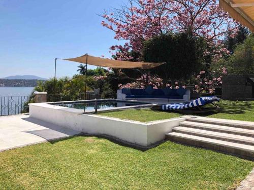 een zwembad in een tuin naast het water bij Casa en Teques con alberca, vista y acceso al lago in Tequesquitengo