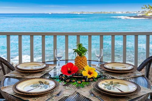 a table with plates and pineapple on the beach at Sea Village 1105 in Kailua-Kona