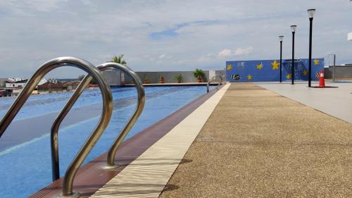 a swimming pool with a metal hand rail next to it at Countryside Condo @One Residence Sekinchan in Sekincan