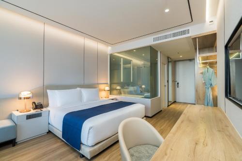 a bedroom with a bed and a table and a chair at Arbour Hotel and Residence in Pattaya Central